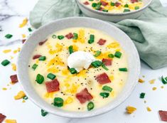 two bowls filled with soup sitting on top of a white marble counter next to green napkins