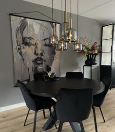 a dining room table with black chairs and a painting on the wall