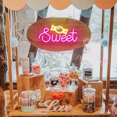 candy bar with neon sign and candies on display in front of window at outdoor event