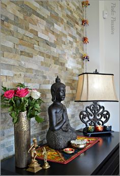 a buddha statue sitting on top of a table next to a vase with flowers in it