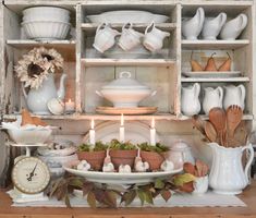 a table topped with dishes and candles next to a shelf filled with plates and bowls