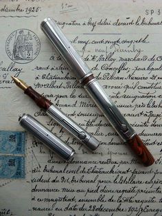 two fountain pens sitting on top of an old paper