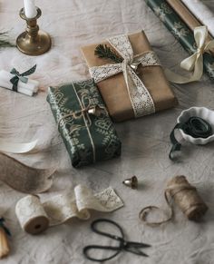 several wrapped presents on a table next to some candles and other decorative items with ribbons