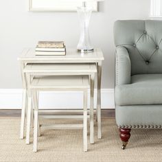 two small tables are sitting next to each other in front of a chair and lamp