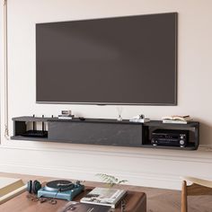 a flat screen tv mounted to the side of a wall next to a wooden table