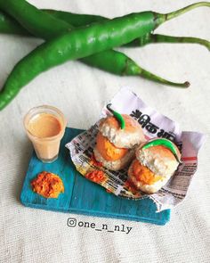 some food is sitting on a blue tray next to green peppers and a cup of sauce