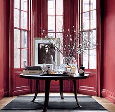 a living room with red walls and striped rug