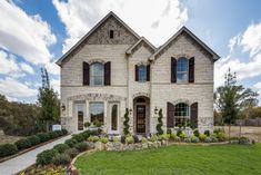 a large house with two story windows and lots of greenery on the front lawn