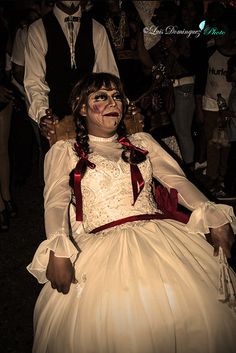 a woman in a white dress sitting on top of a chair next to other people