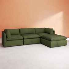 a large green couch sitting on top of a white floor next to an orange wall