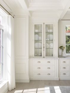 a kitchen with white cabinets and windows