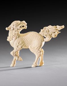 a white figurine of a horse on a gray surface with an intricately carved design