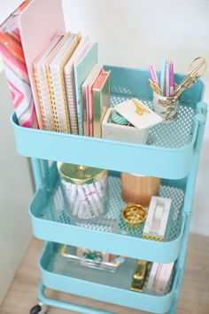 a blue cart filled with lots of books and office supplies on top of a wooden floor