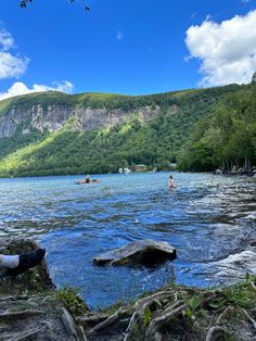 people are swimming in the water near some mountains