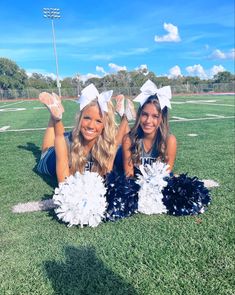 two cheerleaders pose on the football field