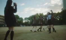 a group of young women standing next to each other on top of a dirt field