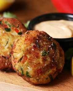 two crab cakes on a cutting board with dipping sauce