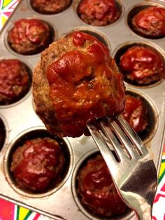 a fork in a muffin tin filled with meatballs