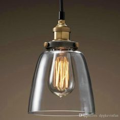 a glass light fixture hanging from the ceiling, with an antique style bulb and metal fittings