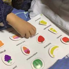 a child's hand on top of a paper with fruit and vegetables