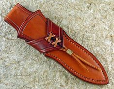 a brown leather sheath with a tassel on it sitting on some hay or grass