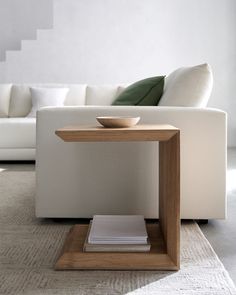 a white couch sitting next to a table with a bowl on it's top