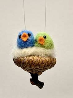 two small birds sitting on top of a bird feeder hanging from strings with needles attached to it