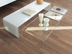 a glass coffee table sitting on top of a wooden floor next to a white couch