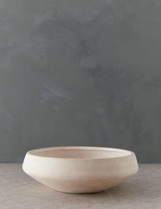 a white bowl sitting on top of a table next to a gray wall and floor