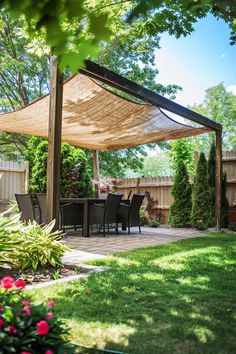 an outdoor patio with a table and chairs under a large shade sail over the dining area