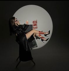 a woman in black dress and high heeled shoes holding up a bag with the word end written on it