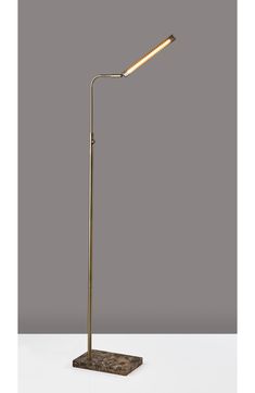 a floor lamp that is on top of a white tablecloth with a gray wall in the background