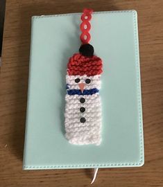 a crocheted snowman ornament hanging from a hook on a table