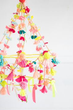 a colorful chandelier hanging from the ceiling with ribbons and flowers attached to it