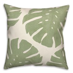 a green and white pillow with large leaves on it