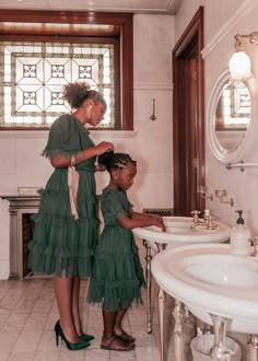 a mother and daughter in the bathroom brushing their hair