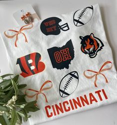 Designed by Aster & Iris, this Bengals Collage T-Shirt is both cute and unique! Includes bows, footballs, a helmet, the Bengals "B" and tiger, and Ohio. What more do you need? Available on a white comfort color t-shirt that runs true to size. If we're out of your size or you need a special size, please contact us to order. Bengals Outfit, Shirt Ideas Women, Local Gifts, White Comforter, Circuit Projects, Email Design, Comfort Color, Kids Jewelry, Cute Fits