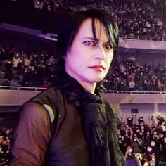 a woman with black hair standing in front of an audience at a concert or show