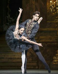 two ballerinas in black and gold outfits on stage