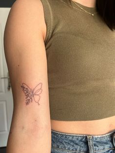 a woman's arm with a small butterfly tattoo on the left side of her arm