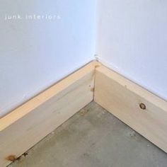 the corner of a room that is being built with unfinished plywood and concrete flooring