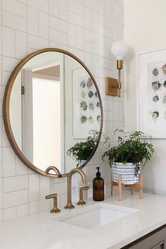 a bathroom sink with a mirror above it and plants on the counter next to it