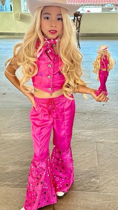 a barbie doll dressed in pink and wearing a cowboy hat with her hands on her hips