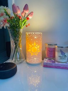 a vase filled with pink flowers next to a candle and some books on a table