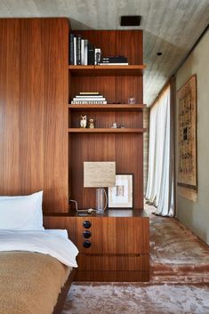 a bed sitting next to a wooden book shelf