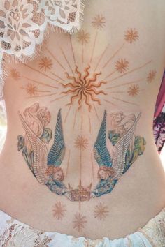 a woman's stomach with tattoos on it and an angel in the sky above her