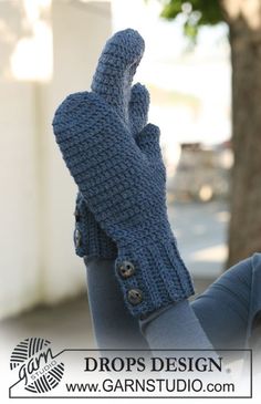 a woman is holding her hand up to the camera and wearing a blue knitted mitt