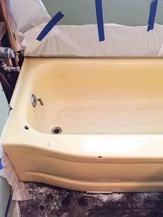 an old bathtub with blue tape on it and the tub is being worked on