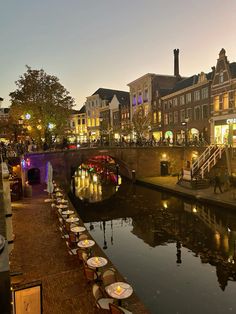 an image of a city at night with tables and chairs lined up along the river