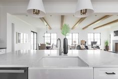 a kitchen with white counter tops and two lamps hanging over the sink in front of it